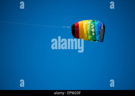 Rainbow kite flying in a cloudless blue sky Stock Photo