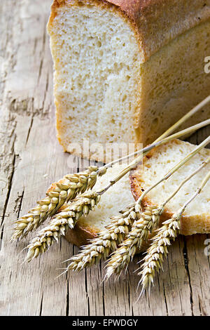 a loaf of bread and wheat ears in the background Stock Photo