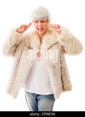 Senior woman standing with fingers in her ears Stock Photo