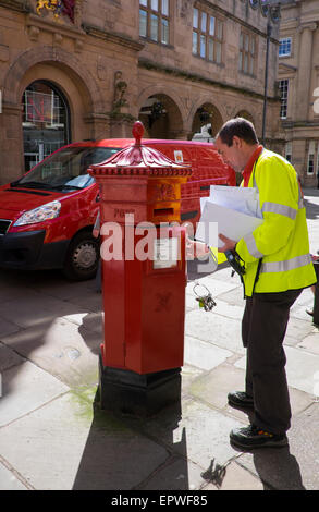 Postman collecting post from a Penfold pillar box in the Square, Shrewsbury, Shropshire, England, UK Stock Photo