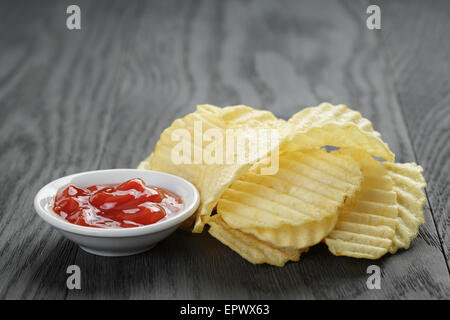 rippled organic chips wit tomato sauce on wooden table Stock Photo