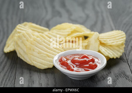 rippled organic chips wit tomato sauce on wooden table Stock Photo