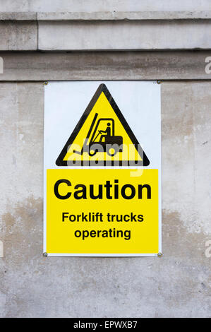 Yellow Caution Forklift trucks operating warning sign. Stock Photo