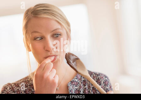 Woman licking batter off spoon Stock Photo