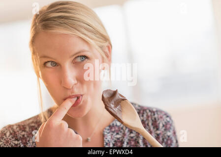 Woman licking batter off spoon Stock Photo