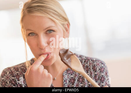 Woman licking batter off spoon Stock Photo