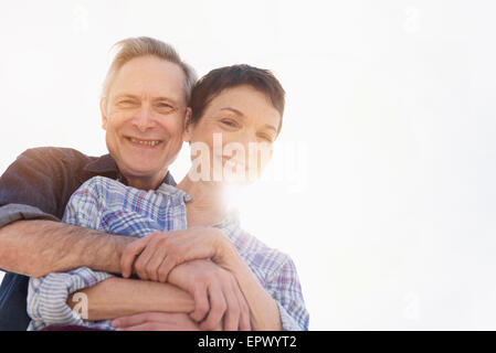 Portrait of smiling senior couple embracing in sunlight Stock Photo
