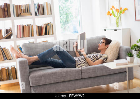 Senior woman reading book on sofa Stock Photo