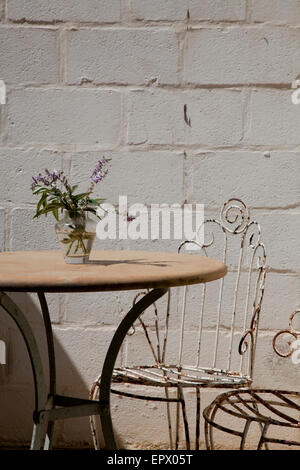 Marble cafe style table with wrought iron chairs and vase of lavender in South African home Stock Photo