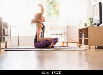 Side-view of woman exercising in living room Stock Photo