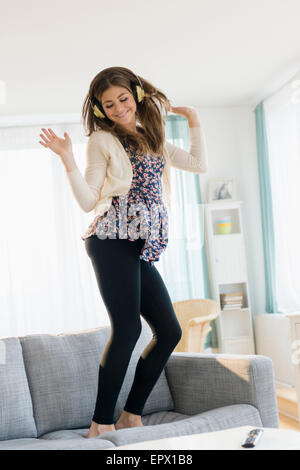 Young woman listening music and dancing on sofa Stock Photo