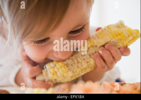 Girl (2-3) eating sweet corn Stock Photo