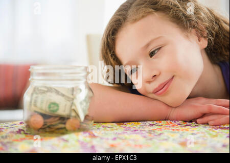 Girl (10-11) girl looking at jar full of money Stock Photo