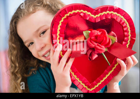 Portrait of girl (10-11) with heart-shaped chocolate box Stock Photo