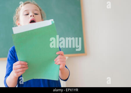 Girl reading in front of chalkboard Stock Photo