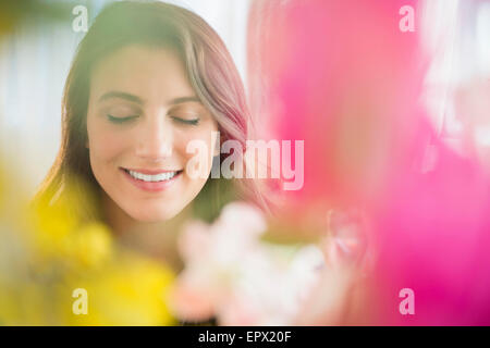 Smiling woman behind blurred flowers Stock Photo
