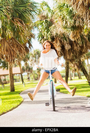 USA, Florida, Jupiter, Young woman riding bicycle in park Stock Photo