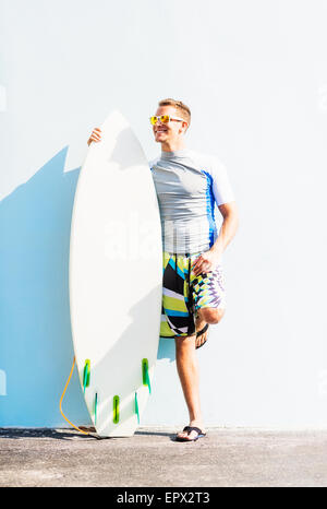 Young surfer leaning against wall Stock Photo