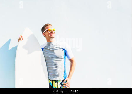 Young surfer leaning against wall, looking up Stock Photo