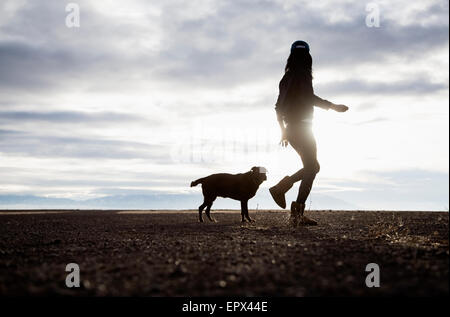 USA, Colorado, Woman walking with dog at sunrise Stock Photo