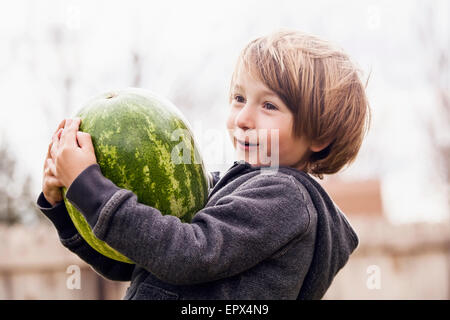 Boy (6-7) carrying watermelon Stock Photo