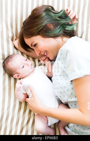 Smiling mother lying on bad with baby boy (6-11 months) Stock Photo