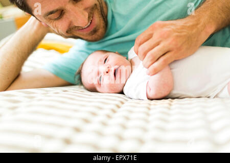 Father with baby boy (6-11 months) on bed Stock Photo