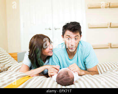 Happy parents playing with baby boy (6-11 months) on bed Stock Photo
