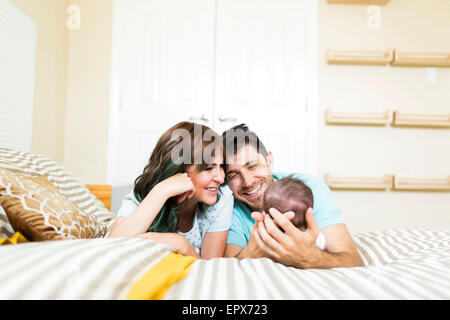 Happy parents playing with baby boy (6-11 months) on bed Stock Photo