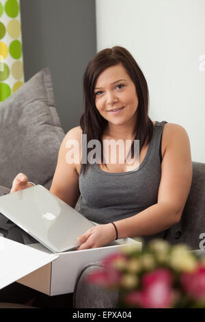 Young woman taking out a new laptop from it's packaging. Stock Photo