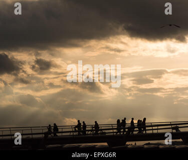 London, UK. 22nd May, 2015. Pedestrians are silhouetted against a spectacular sunset sky as they walk across London's Millennium Bridge Credit:  Patricia Phillips/Alamy Live News Stock Photo