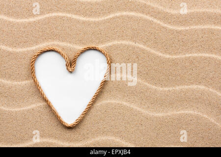 Heart made of rope with a white background on the sand, with place for your text Stock Photo