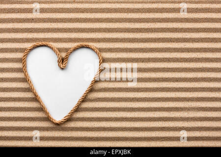 Heart made of rope with a white background on the sand, with place for your text Stock Photo