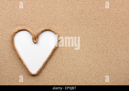 Heart made of rope with a white background on the sand, with place for your text Stock Photo