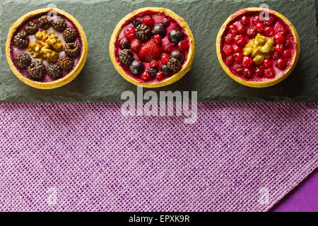 Three autumn fruits cakes on a slate plate on purple background Stock Photo