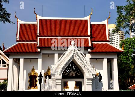 Bangkok, Thailand:  Ornamental entrance gateway and Ubosot sanctuary hall with gilded chofah ornaments at Wat Pathum Wanaram Stock Photo