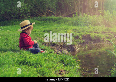 Cute baby boy with fishing rod standing by river on sunny day Stock Photo -  Alamy