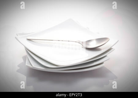 stack of square plates with a spoon isolated on a white background ...