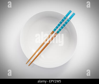 chopsticks in empty bowl isolated on a white background Stock Photo