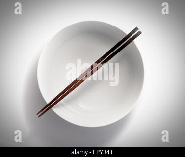 chopsticks in empty bowl isolated on a white background Stock Photo