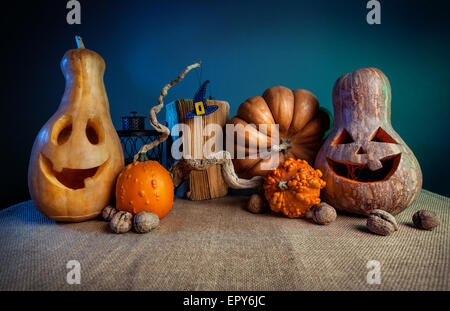 Carved pumpkins, old book, nuts and witch hat from felt on the branch at Halloween party Stock Photo