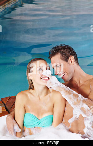 Happy young couple having fun in whirlpool with bubble foam bath