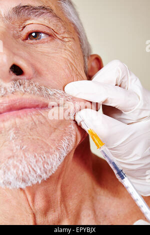 Old man getting cosmetic surgery on corner of mouth in beauty clinic Stock Photo