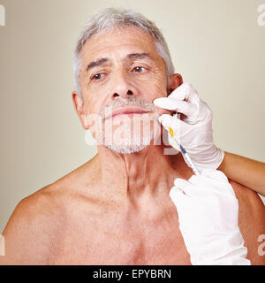 Old man getting wrinkle treatment with hyaluronic acid in beauty parlor Stock Photo
