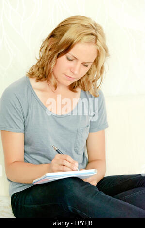Young woman making notes in notebook Stock Photo