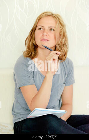 Young woman thinking over making notes in notebook Stock Photo