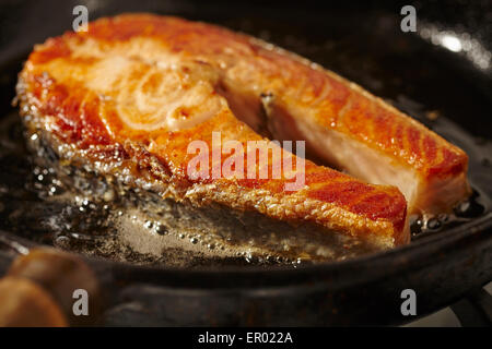 Salmon steak frying in a cast iron pan Stock Photo