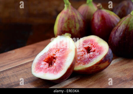 Fresh figs on wooden cutting chopping board on dark wood rustic table background. Stock Photo