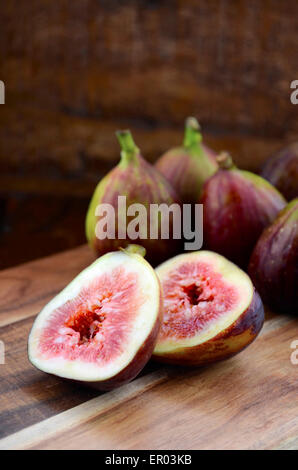Fresh figs on wooden cutting chopping board on dark wood rustic table background. Stock Photo