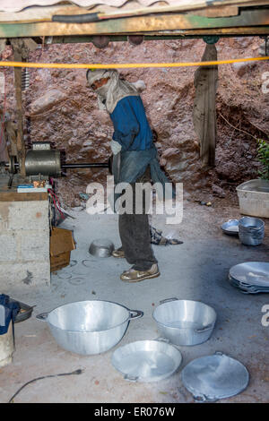 Metal worker grinding aluminum kitchen bowls and cookware to remove rough edges after molding process in Guatemala Stock Photo